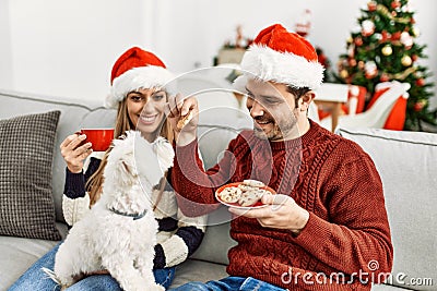 oung hispanic couple wearing christmas hat drinking coffee and eating cookies Stock Photo