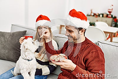 oung hispanic couple wearing christmas hat drinking coffee and eating cookies Stock Photo