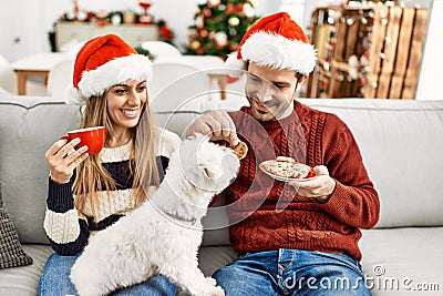 oung hispanic couple wearing christmas hat drinking coffee and eating cookies Stock Photo