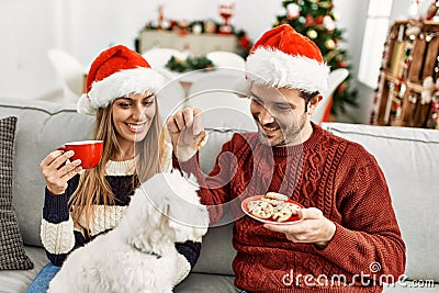 oung hispanic couple wearing christmas hat drinking coffee and eating cookies Stock Photo