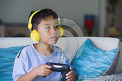 Oung hispanic little kid excited and happy playing video game online with headphones holding controller enjoying having fun sittin Stock Photo