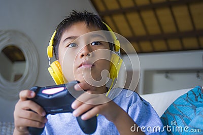 Oung hispanic little kid excited and happy playing video game online with headphones holding controller enjoying having fun sittin Stock Photo