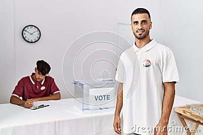 oung hispanic voter wearing vote badge standing at electoral center Stock Photo