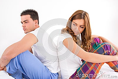 ouple sitting in bed side by side and getting sad after an argument Stock Photo