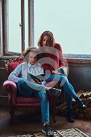 Young students reading together and sitting on a chair. Stock Photo