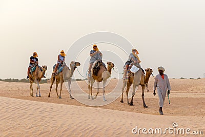 Tourists ride on camels guided by a local man, in the Sahara desert, Tunisia, Africa Editorial Stock Photo