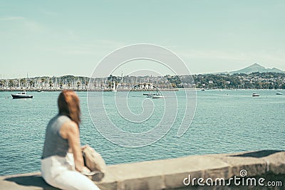 out-of-focus woman observing a bay with seafaring ships Stock Photo