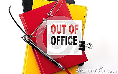 OUT OF OFFICE text written on a sticky on colorful notebooks Stock Photo