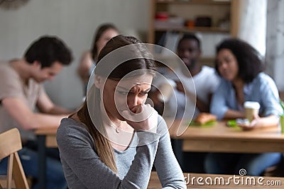 Outcast girl sitting separately by others teenagers in cafe Stock Photo