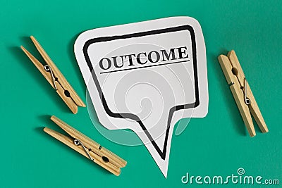 OUTCOME - word on white sticky note with wooden clothespins on green background Stock Photo