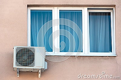 An outdoor air conditioner unit installed on the wall of a residential building next to the window. Installation, repair and Stock Photo