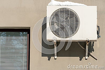 An outdoor air conditioner unit installed on the wall of a residential building next to the window. Installation, repair and Stock Photo