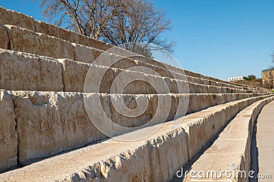 Outdoor amphitheater with large limestone blocks arranged in long rows, designed for seating in a public space, on a sunny Stock Photo