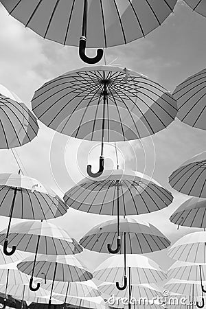 Outdoor art design and decor. Umbrellas float in sky on sunny day. Umbrella sky project installation. Holiday and Editorial Stock Photo