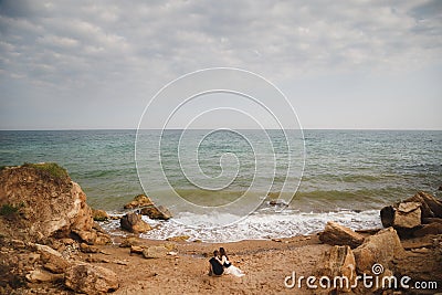 Outdoor beach wedding ceremony, stylish wedding loving couple is sitting near the sea Stock Photo