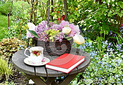 Afternoon tea outdoors in spring flower garden with English tea in fancy teacups Stock Photo