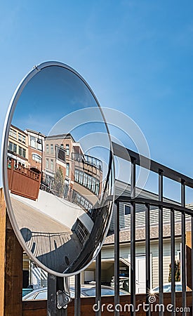 Outdoor convex safety mirror hanging on wall with reflection. Round mirror on a post to help cornering transport Stock Photo