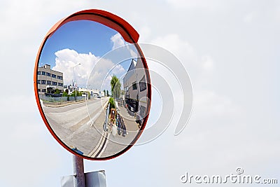 Outdoor convex safety mirror hanging on wall with reflection of an urban roadside view of cars parked along the street Stock Photo
