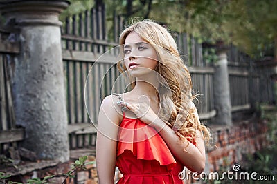 Outdoor fashion beautiful young woman photo near old HOMESTEAD summer. Portrait girl blondes in red dress. Stock Photo