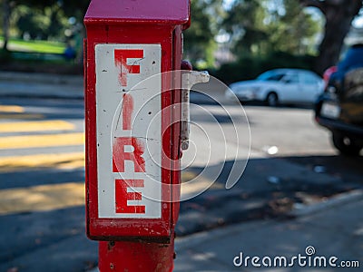 Outdoor fire alarm call box at urban intersection, fire in bold font Stock Photo