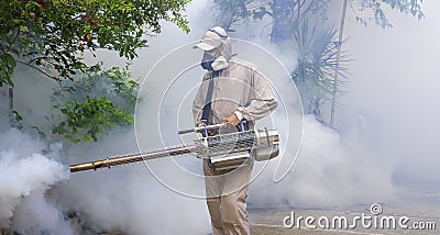 Healthcare worker using fogging machine spraying chemical to eliminate mosquitoes on overgrown at slum area Stock Photo