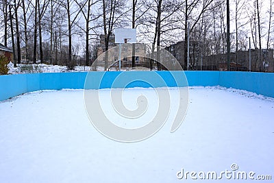 An outdoor ice skating rink and a hockey net with tall frost covered trees in the background in a winter landscape Stock Photo