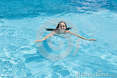 Outdoor image of cheerful adorable young lady enjoying active pasttime, fond of leisure activities, swimming in swimming pool Stock Photo