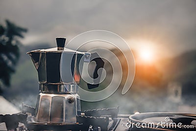 Outdoor kitchen equipment camp fire and brewing tea pot moka coffee drip cup,with wooden table camping gas stove set in nature Stock Photo