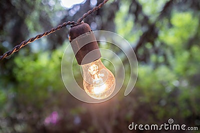 An outdoor lightbulb glowing yellow at dusk Stock Photo