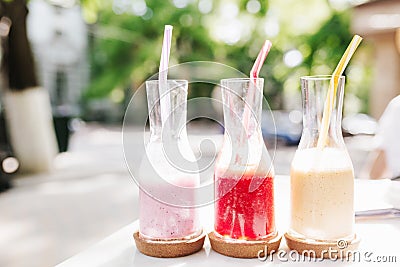 Outdoor photo of three bottles of tasty fruit cocktails. Close-up picture of glasses with smoothie standing on blur Stock Photo