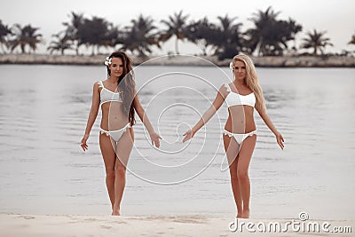 Outdoor photo of two sexy bikini girls models in fashion swimsuits on tropical beach at Maldives island. Slim ladies with tan Stock Photo