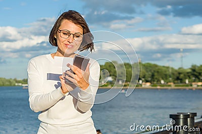 Outdoor portrait attractive happy middle aged woman female freelancer blogger traveler with phone on nature Stock Photo