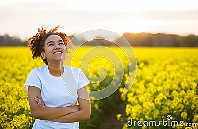 Mixed Race African American Girl Teenager Smiling Happy In Yellow Flowers Stock Photo