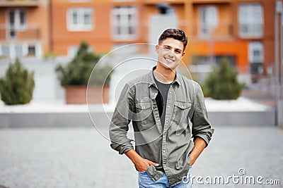 Outdoor portrait of handsome young man walking on the street, looking at camera and smile Stock Photo