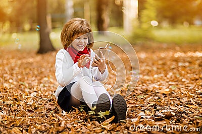 Outdoor portrait of little girl playing with phone. Happy child girl using smartphone Stock Photo