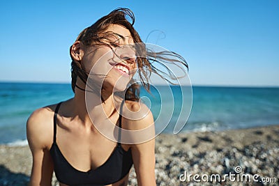 Outdoor portrait pleased woman enjoying sunshine at sea beach against blue sky Stock Photo