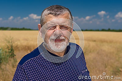 Ortrait of Ukrainian bearded Caucasian senior farmer against crop field and blue sky Stock Photo