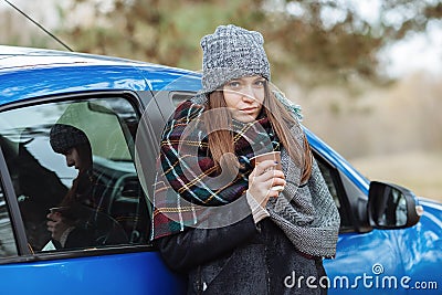 Outdoor portrait of young caucasian woman, holding a cup of takeaway coffee in forest park on cold season day. Dressed in an Stock Photo