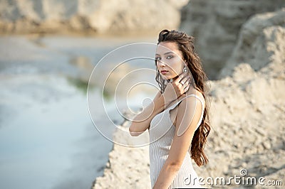 Outdoor portrait of young sexy tanned beautiful woman standing on sand near the sea Stock Photo