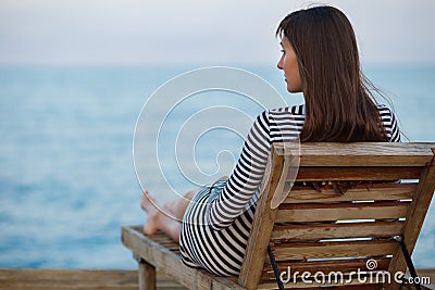 Outdoor portrit of beautiful young woman relaxing at the seacoast at the evening Stock Photo