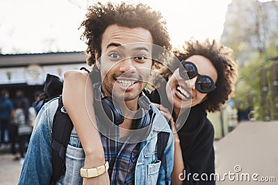 Outdoor protrait of african-american couple hugging and smiling broadly at camera while walking in park and expressing Stock Photo