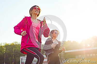 Running sporty mature mother and teen daughter. Stock Photo