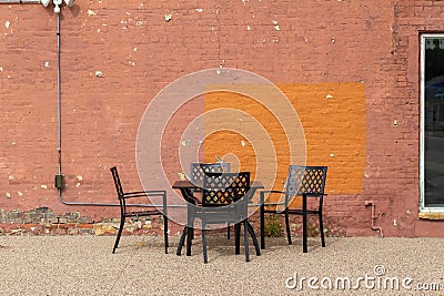 Outdoor table and chairs in front of an artsy looking old salmon color painted brick wall Stock Photo