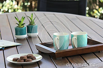 Outdoor table setting with cookies, two turquoise coffee cups, book, flowers Stock Photo