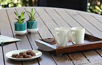 Outdoor table setting with cookies, two white coffee cups, book, flowers Stock Photo