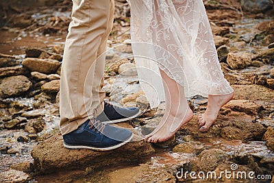 Outdoor wedding ceremony, close up of young woman feet standing barefoot on stones in front of mans feet wearing dark blue shoes Stock Photo