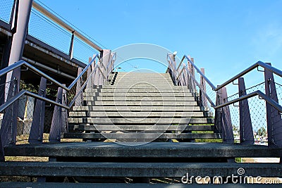 Outdoor wide concrete stairs surrounded with inox handrails and wire net protection leading to local train station Stock Photo