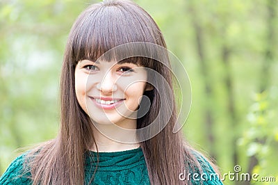 Outdoors closeup portrait of young beautiful woman brunette girl happy smiling & looking at camera on summer green background Stock Photo