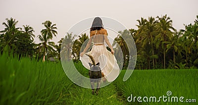 Outdoors holidays portrait of attractive and happy Asian woman in white dress enjoying beauty of nature walking her dog at Stock Photo