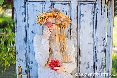 Outdoors lifestyle close up portrait of charming blonde young woman wearing a wreath of autumn leaves. Wearing stylish Stock Photo